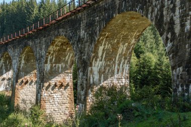 Dağlardaki büyük, eski bir su kemeri köprüsü.