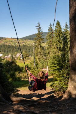 Genç bir kız büyük bir salıncakta sallanıyor Dağlarda nefes kesici bir manzarayla