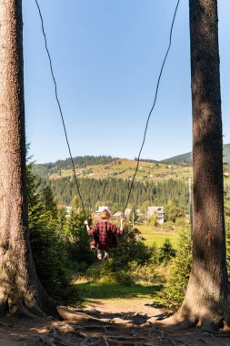 Genç bir kız büyük bir salıncakta sallanıyor Dağlarda nefes kesici bir manzarayla