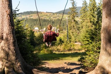 Genç bir kız büyük bir salıncakta sallanıyor Dağlarda nefes kesici bir manzarayla