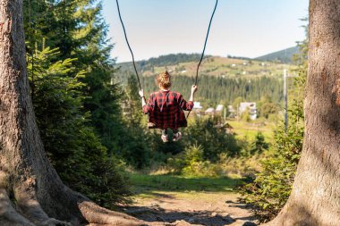 Genç bir kız büyük bir salıncakta sallanıyor Dağlarda nefes kesici bir manzarayla