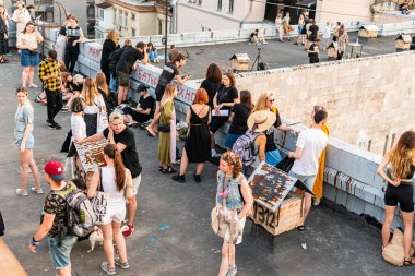 Kyiv (Kiev), Ukraine - July 17, 2021: A lot of young people on the roof chilling and enjoying time on a warm sunny day, demonstrating against demolition of a historical building Kvity Ukrayiny (Flowers of Ukraine)