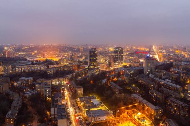 Ukrayna, Kyiv 12 Mart 2016: Gökyüzü panoramik manzarası Kyiv şehrinin orta kesiminde yüksek bir binanın çatısından görülüyor. Büyük bir şehirde gece hayatı. Sisli ve yağmurlu hava. 