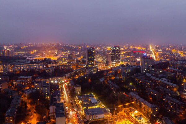 Ukraine, Kyiv March 12, 2016: Aerial panoramic view on central part of Kyiv city from a roof of a high-rise building. Night life in a big city. Foggy and rainy weather.