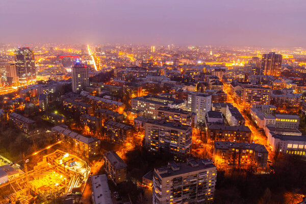 Ukraine, Kyiv March 12, 2016: Aerial panoramic view on central part of Kyiv city from a roof of a high-rise building. Night life in a big city. Foggy and rainy weather.