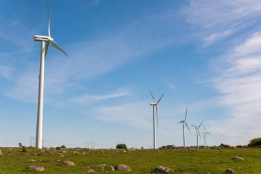 İsveç, Kristianstad 17 Mayıs 2022: Büyük rüzgar türbinleri, açık havada elektrik jeneratörleri, mavi gökyüzü. 