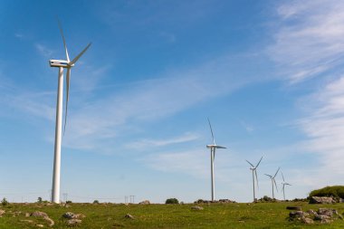 İsveç, Kristianstad 17 Mayıs 2022: Büyük rüzgar türbinleri, açık havada elektrik jeneratörleri, mavi gökyüzü. 