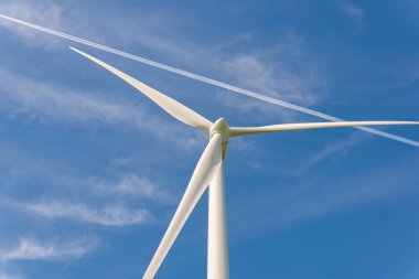 Sweden, Kristianstad  May 17, 2022: Huge wind turbines, electrical energy generators in a field outdoors, blue sky. 