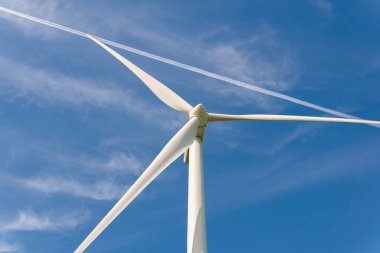 Sweden, Kristianstad  May 17, 2022: Huge wind turbines, electrical energy generators in a field outdoors, blue sky. 