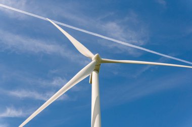 Sweden, Kristianstad  May 17, 2022: Huge wind turbines, electrical energy generators in a field outdoors, blue sky. 