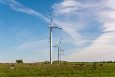 İsveç, Kristianstad 17 Mayıs 2022: Büyük rüzgar türbinleri, açık havada elektrik jeneratörleri, mavi gökyüzü. 