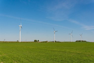 İsveç, Kristianstad 17 Mayıs 2022: Büyük rüzgar türbinleri, açık havada elektrik jeneratörleri, mavi gökyüzü. 