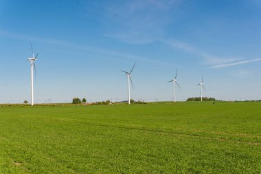 İsveç, Kristianstad 17 Mayıs 2022: Büyük rüzgar türbinleri, açık havada elektrik jeneratörleri, mavi gökyüzü. 