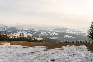 Ormanlı, kayalı, devasa karlı dağlar. Panorama en üstte, hava manzaralı. Dağlarda ıssız bir ev..