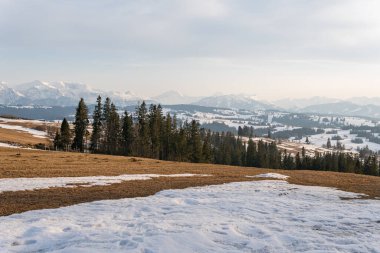 Ormanlı, kayalı, devasa karlı dağlar. Panorama en üstte, hava manzaralı. Dağlarda ıssız bir ev..