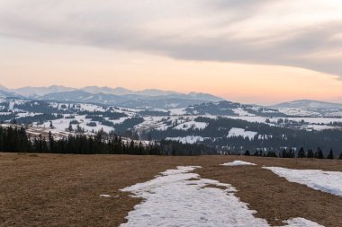 Ormanlı, kayalı, devasa karlı dağlar. Panorama en üstte, hava manzaralı. Dağlarda ıssız bir ev..