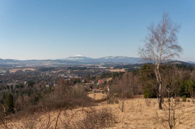 İlkbaharda karlı dağların ve tepelerin nefes kesici manzarası, orman ve köy, panoramik manzara 