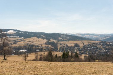İlkbaharda karlı dağların ve tepelerin nefes kesici manzarası, orman ve köy, panoramik manzara 