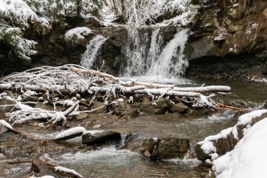 Kışın güzel, küçük şelaleler ormanda, karlı tepelerde, açık havada.