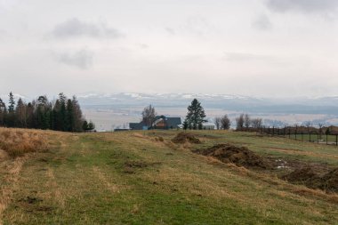 A beautiful panoramic landscape of mountains in grey rainy weather in Europe. Wooden summer house, cottage, beautiful nature. Breathtaking view. 
