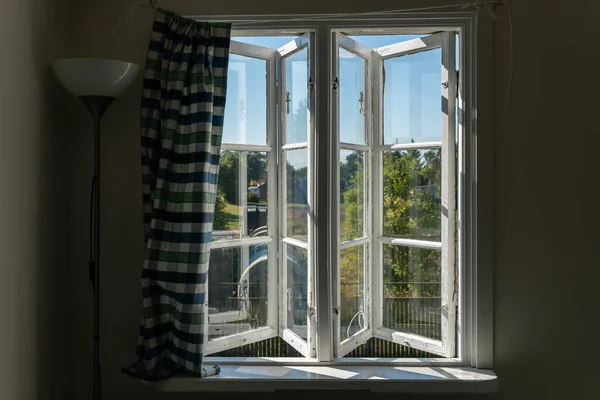 View from open window in the village. White old wooden windows with view on blue sky and green field. Symbol of insouciance, freedom, summer atmosphere. Holiday house, summer cottage, weekend cottage.