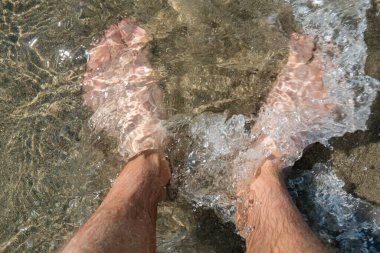 Sahilde ayakta duran ayaklar suyun kumları üzerinde, ferahlatıcı.