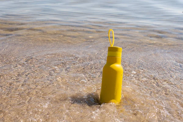 Žlutá Láhev Termoska Stojící Písku Pláži Oceán Slunečného Letního Dne — Stock fotografie