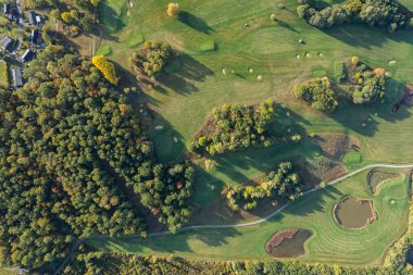 Büyük bir golf sahasının havadan görünüşü, güzel yeşil çimenler, sonbaharda tarlalar ve ağaçlar.