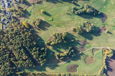 Büyük bir golf sahasının havadan görünüşü, güzel yeşil çimenler, sonbaharda tarlalar ve ağaçlar.