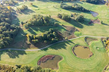 Büyük bir golf sahasının havadan görünüşü, güzel yeşil çimenler, sonbaharda tarlalar ve ağaçlar.