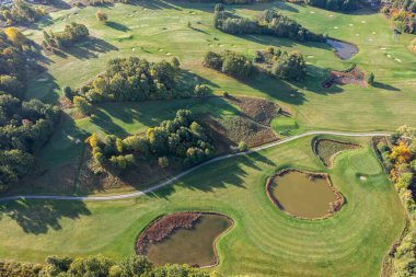 Büyük bir golf sahasının havadan görünüşü, güzel yeşil çimenler, sonbaharda tarlalar ve ağaçlar.