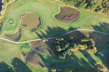 Büyük bir golf sahasının havadan görünüşü, güzel yeşil çimenler, sonbaharda tarlalar ve ağaçlar.