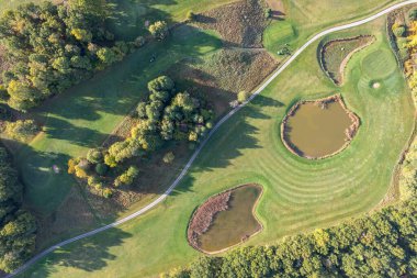 Büyük bir golf sahasının havadan görünüşü, güzel yeşil çimenler, sonbaharda tarlalar ve ağaçlar.