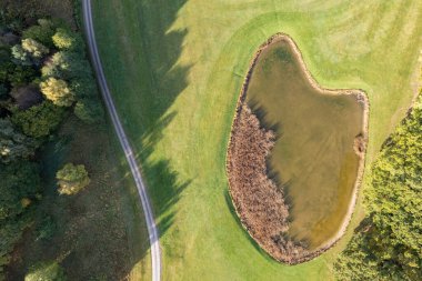 Büyük bir golf sahasının havadan görünüşü, güzel yeşil çimenler, sonbaharda tarlalar ve ağaçlar.