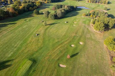 Büyük bir golf sahasının havadan görünüşü, güzel yeşil çimenler, sonbaharda tarlalar ve ağaçlar.