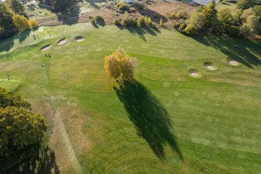 Büyük bir golf sahasının havadan görünüşü, güzel yeşil çimenler, sonbaharda tarlalar ve ağaçlar.