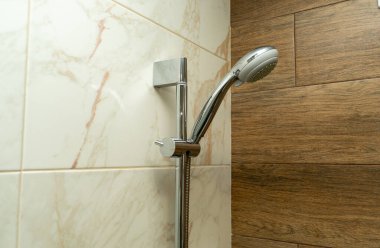 Banyodaki seramik fayans duvarında duş başlığı var.