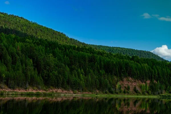 Τοπίο της όχθης του ποταμού στη Σιβηρία. φωτεινά ζουμερά χρώματα λοφώδες όχθη του ποταμού και μπλε σύννεφα — Φωτογραφία Αρχείου