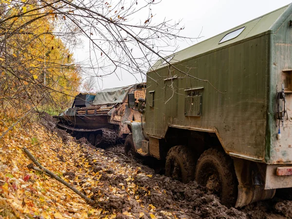 tracked vehicles pull a military truck out of the mud