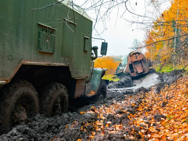 tracked vehicles pull military truck out of the mud