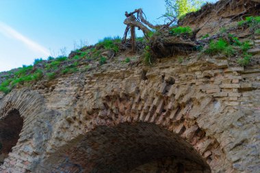 Toprakla kaplı kırmızı tuğladan yapılmış kale duvarının bir parçası.