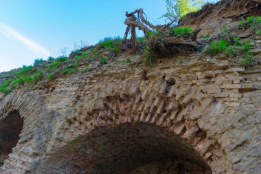 Toprakla kaplı kırmızı tuğladan yapılmış kale duvarının bir parçası.