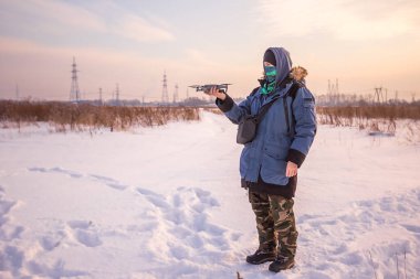 Mavi ceketli, elinde uzaktan kumandayla uçan bir dron fırlatan beyaz bir erkek..