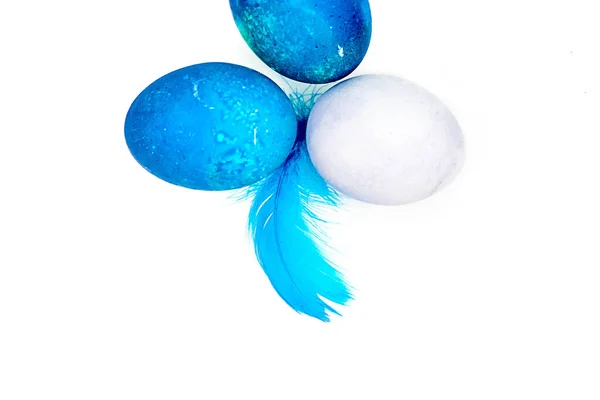 蓝色复活节彩蛋和蓬松的蓝色小羽毛随意散落在白桌子上 — 图库照片