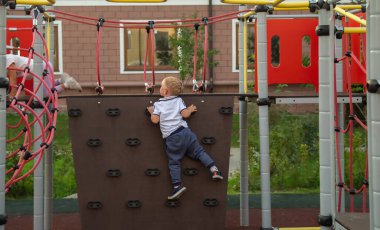Beyaz çocuk oyun parkındaki tırmanma duvarına tırmandı..