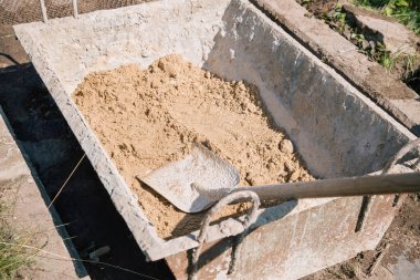 Bahçe yolu açmak için çimento karışımına kum yüklüyorum.