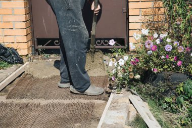 Metal ağın tepesinde çimento döşeyen bahçe yolları, bahçede inşaat işleri..