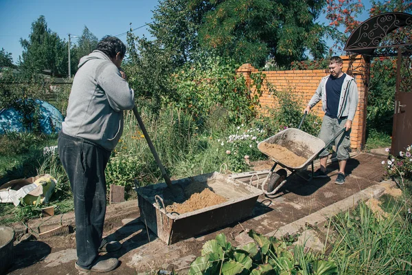 Yaşlı adam bahçe yolu için çimento yoğurur, bahçe inşaatı.