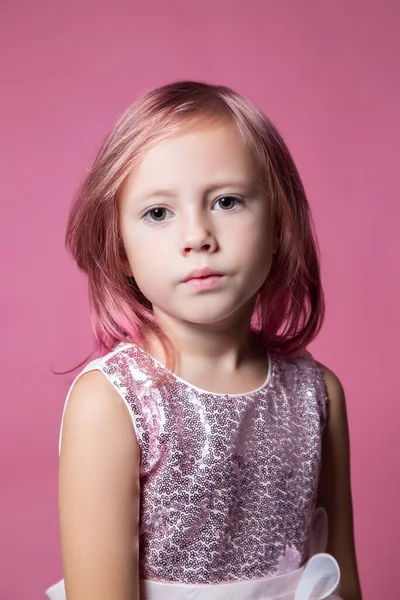 穿着节日礼服的白人小女孩 穿着亮片在粉色背景上摆姿势 看着摄像机 — 图库照片