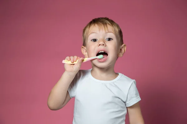 Sorridente ragazzo caucasico che pulisce i denti con lo spazzolino da denti manuale per bambini — Foto Stock